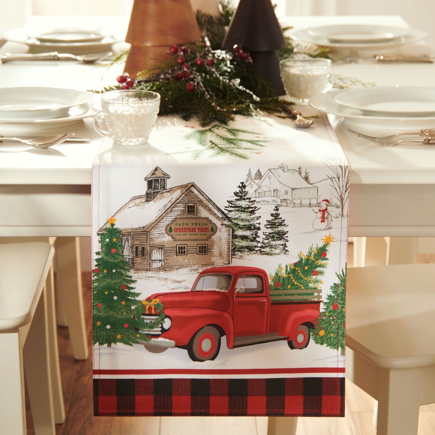 Table runner with vintage tree farm scene and rustic red farm truck on ends. Sprigs of balm running down the center of runner.