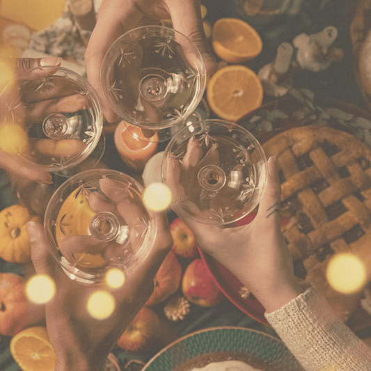 four glasses meeting to cheers over a thanksgiving table