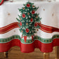 White holiday tablecloth with holly damask designs all over, red ribbon design border and red and green holly and Christmas trees along the ribbon border - closeup of border