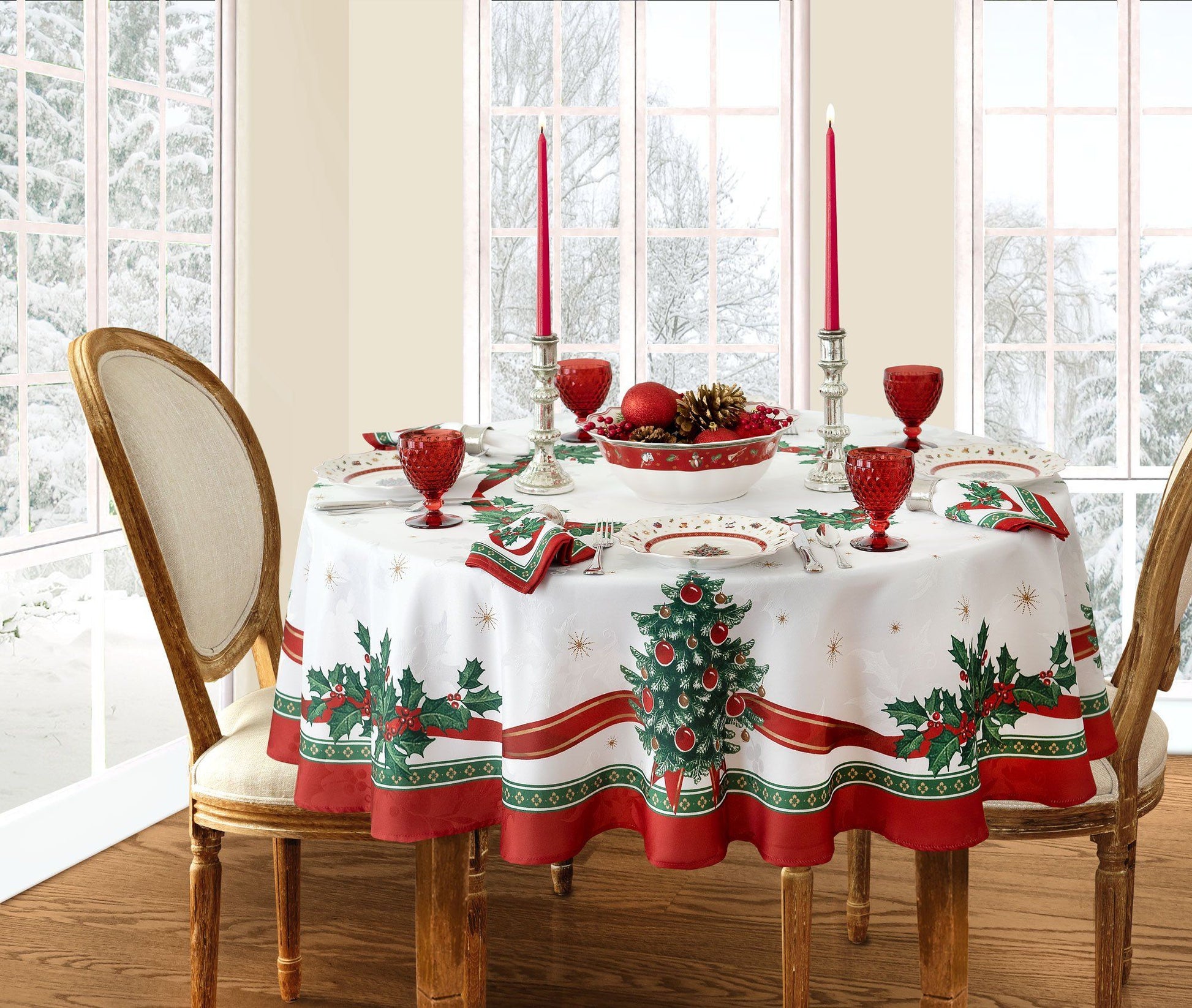 White holiday tablecloth with holly damask designs all over, red ribbon design border and red and green holly and Christmas trees along the ribbon border - round table